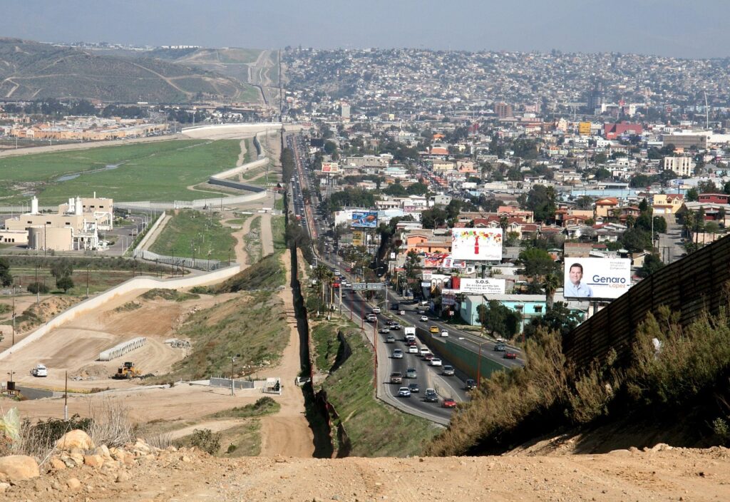 Freight trucks moving through a busy US-Mexico border crossing under customs checks